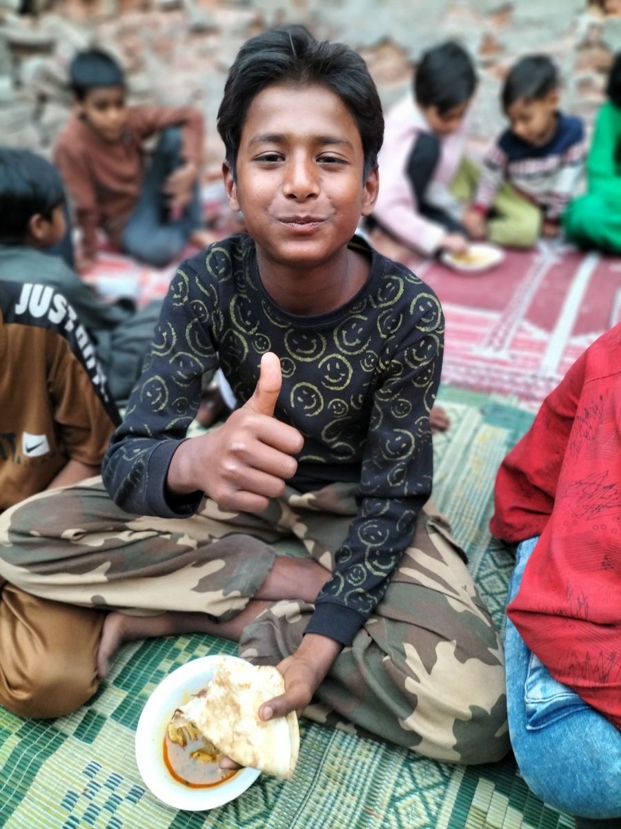 A boy giving a thumbs-up, holding his meal
