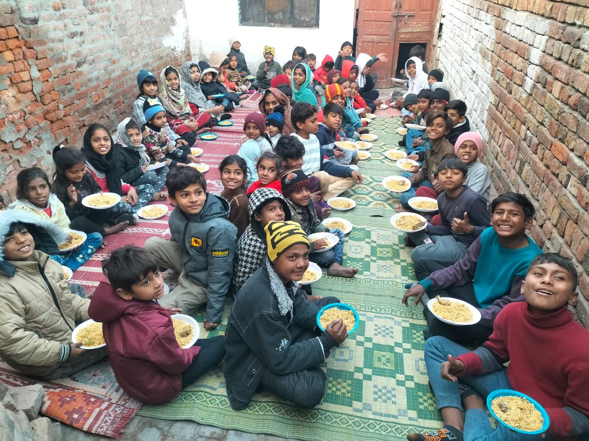 The orphans seated in rows for a meal, dressed warmly
