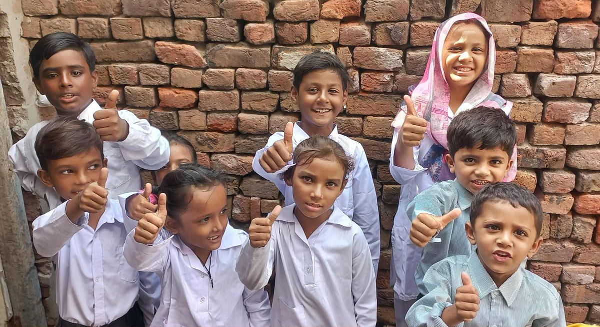 Children in school uniforms giving a thumbs-up