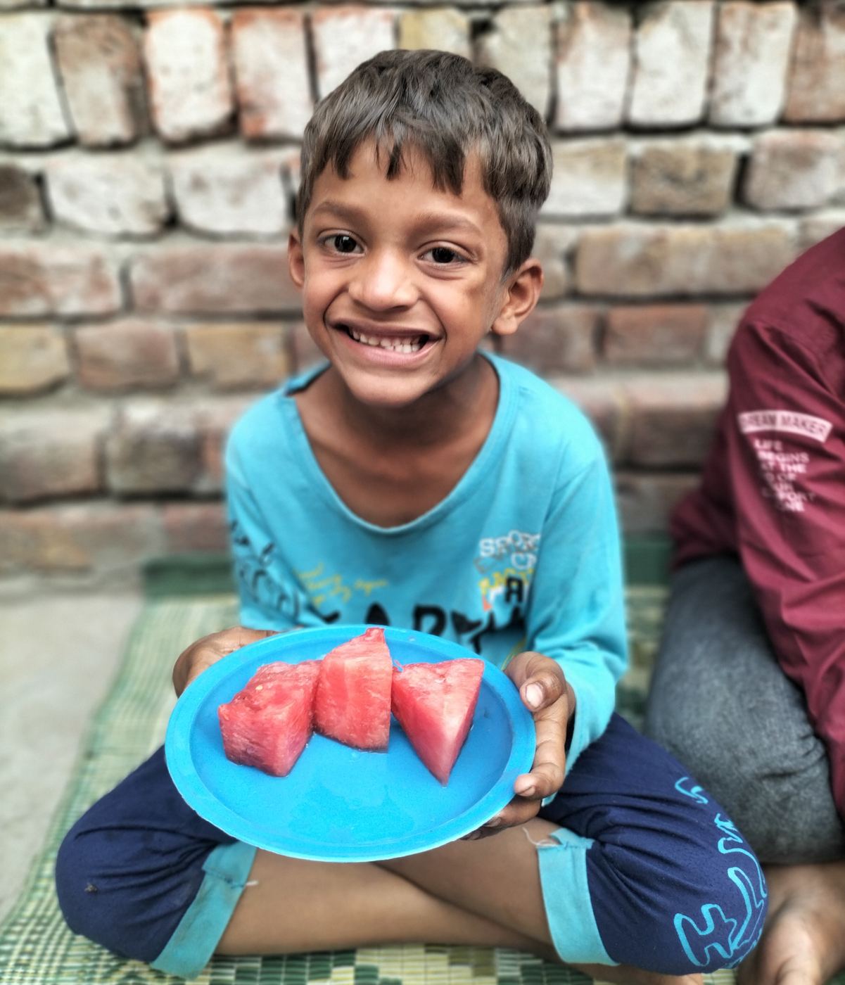 A smiling boy with a plate of watermelon