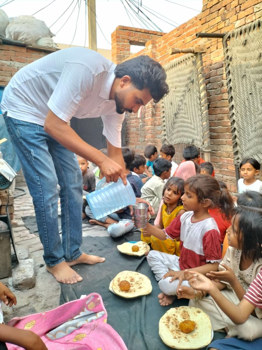 Our missionary pours water into a little girl's cup, seated in a row with other children