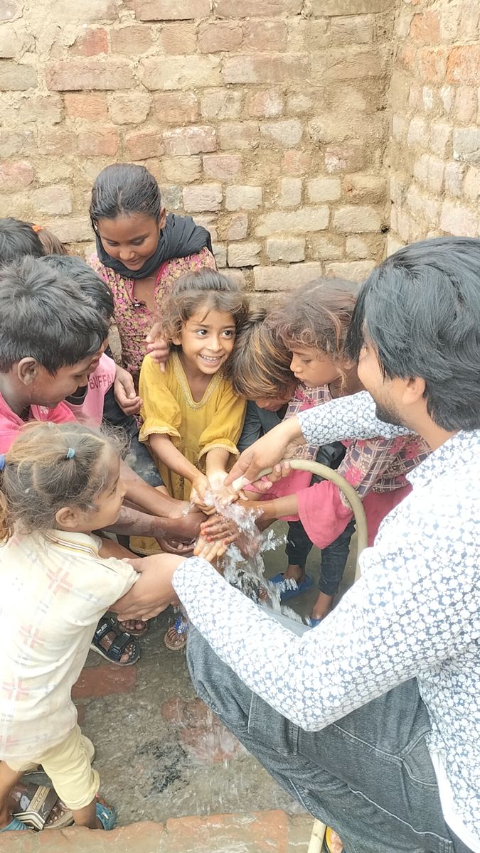 Joyful children washing their hands with water from the well